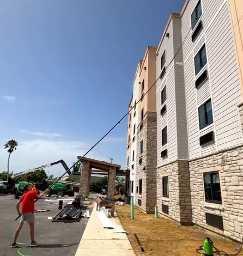 Technician using a boom lift to clean upper-story hotel windows